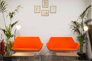 Two orange armchairs in the Kilrush Digital Hub with four pictures on the wall behind them